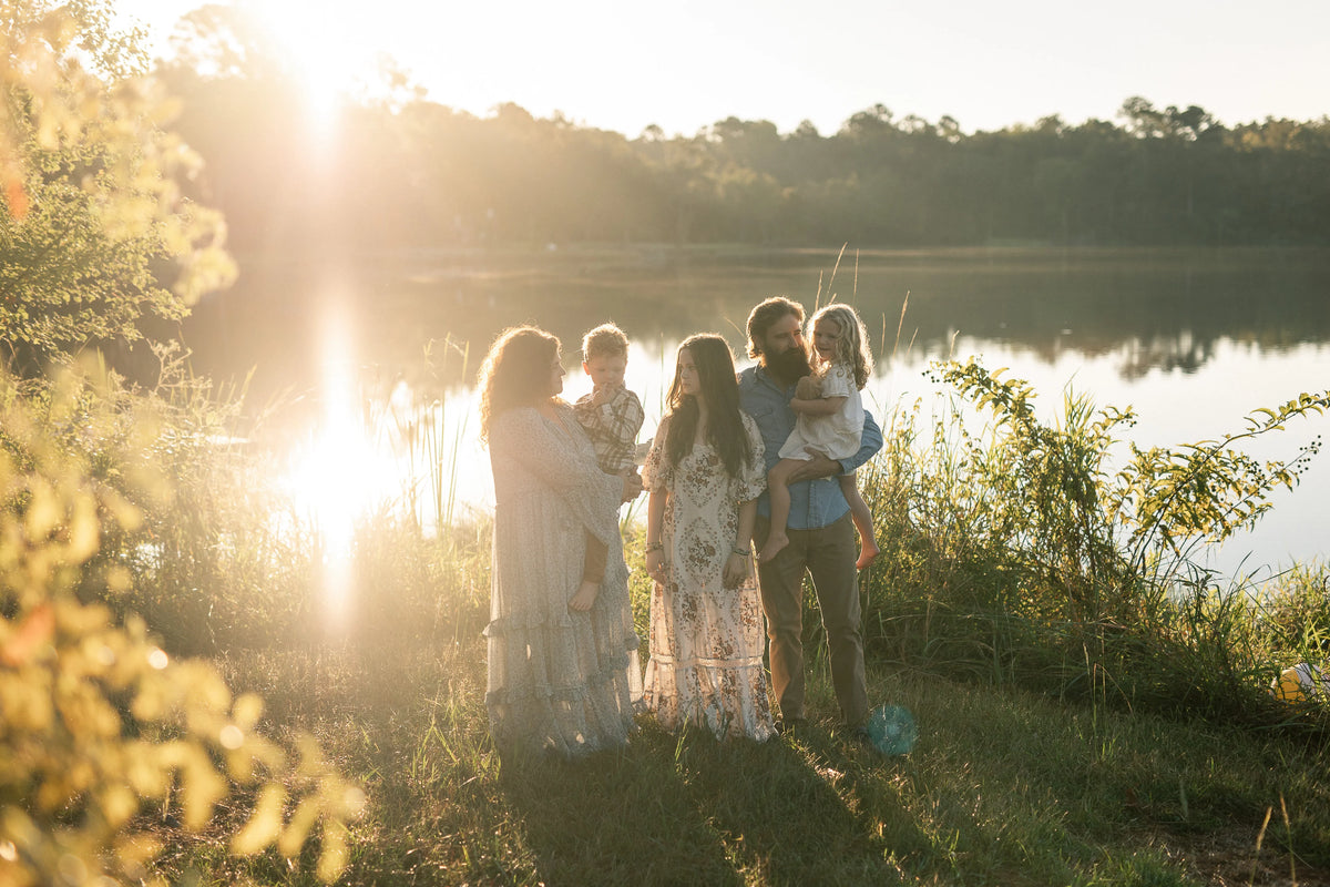 Family of five standing together by a lake at sunset